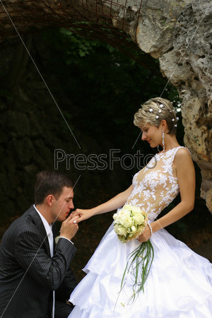 The groom kisses a hand to the bride kneeling