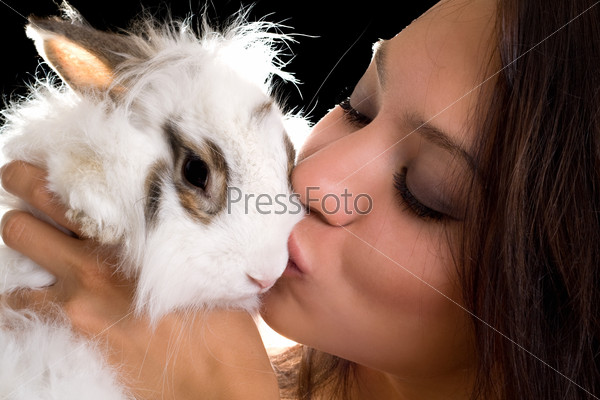 Portrait of young woman kissing little rabbit. Isolated on black