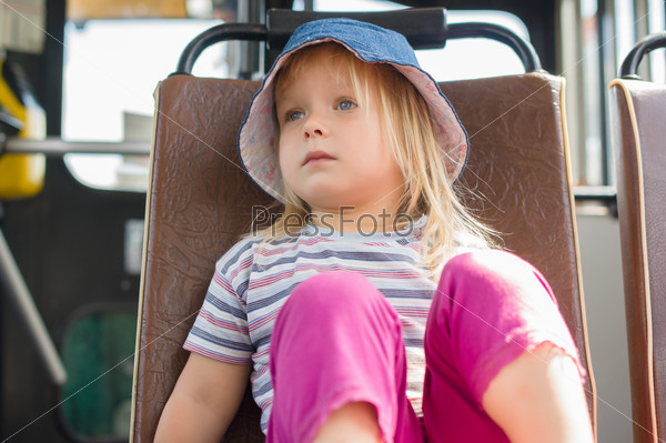 Adorable girl in blue hat ride on bus