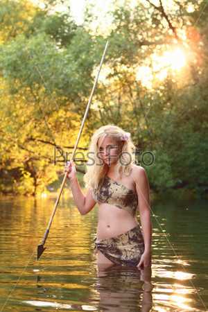 cute savage girl with gaff stands in the water of river