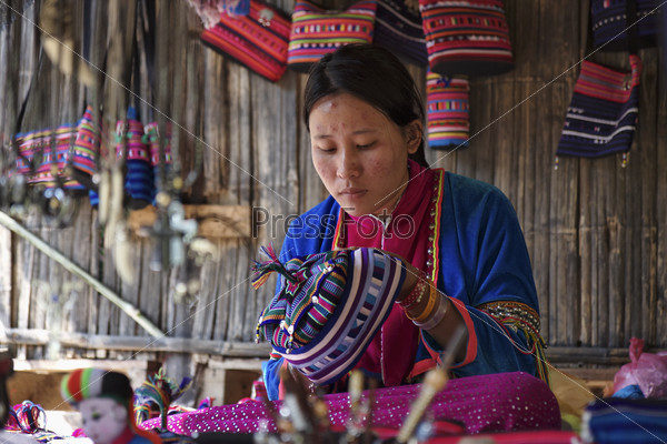 Молодая женщина в традиционном костюме своей деревни, за работой, Таиланд