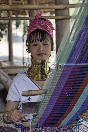 Молодая тайская девушка в традиционном костюме своей деревни, ткет ковер