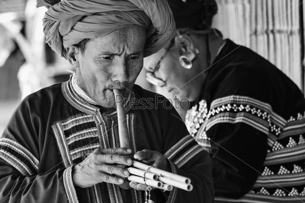Thailand, Chiang Mai, Karen Long Neck hill tribe village (Kayan Lahwi), Karen man in traditional costumes playing a flute
