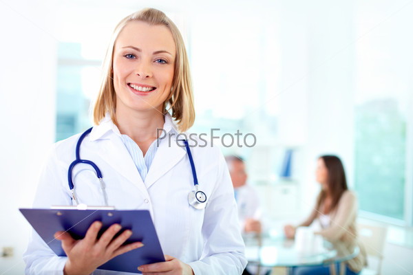 Portrait of pretty female practitioner looking at camera in working environment