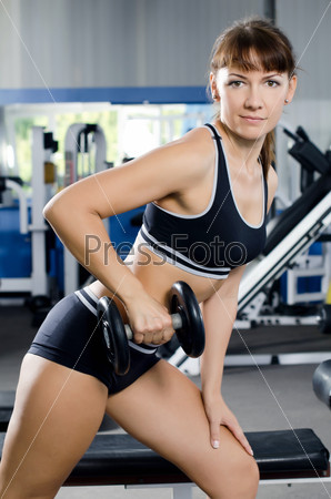 The woman with dumbbells in sports club