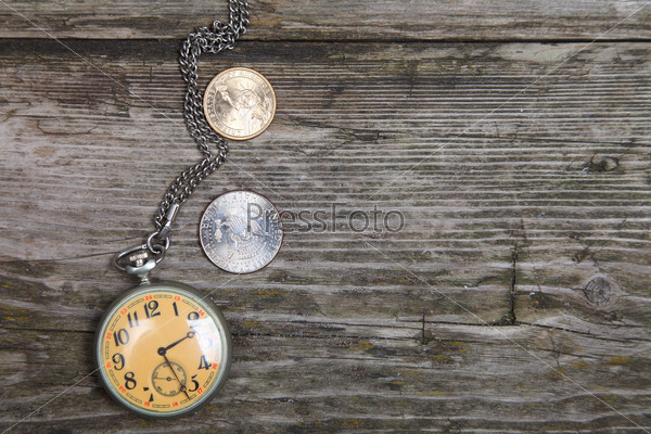 Old clock and U.S. coins on a wooden background