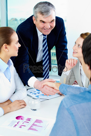 Photo of successful businessmen handshaking after striking deal with partners near by