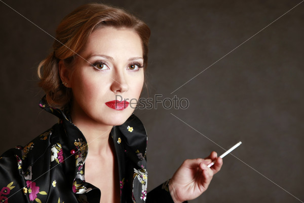 Portrait of the beautiful woman with a cigarette in\
studio