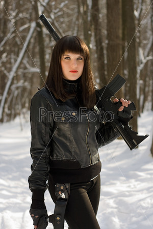 Portrait of beautiful young woman with a rifle in forest
