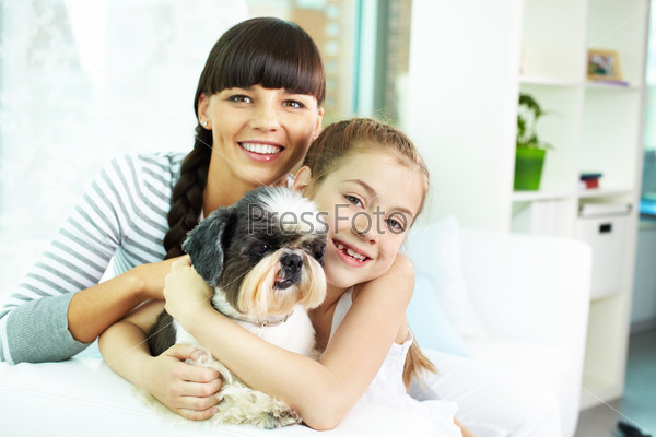 Portrait of happy girl, her mother and their cute pet at home