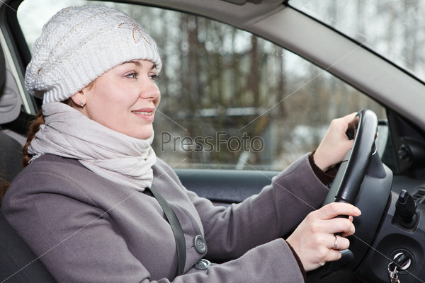 Woman in winter clothes driving car