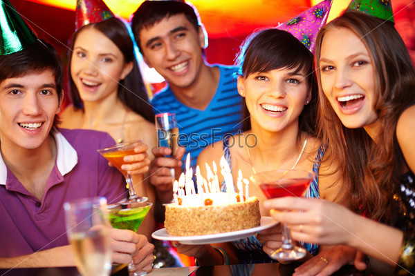 Portrait of joyful friends toasting and looking at camera at birthday party