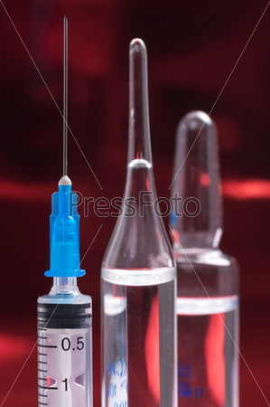 Disposable syringes and ampules on a colored background