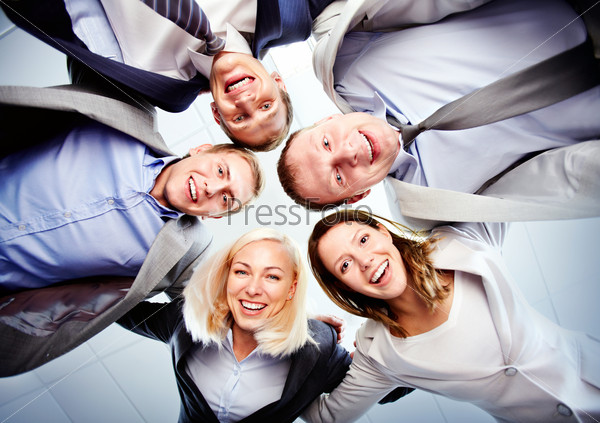 Below View Of Several Happy Business Partners Looking At Camera While Embracing Each Other