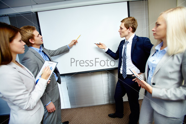 Two confident businessmen pointing at whiteboard while making speech at meeting, stock photo