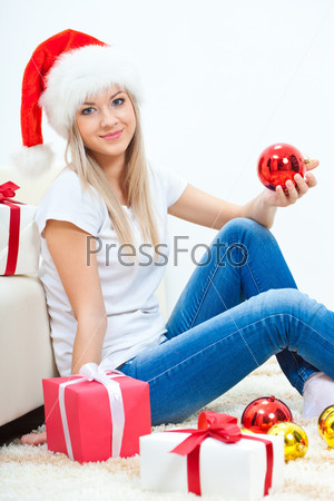 blonde woman wearing santa hat sitting on the floor near sofa
