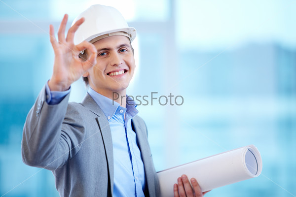 Portrait of cheerful architect signing okay and looking at camera
