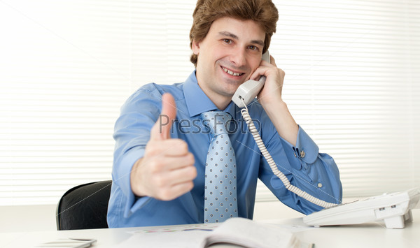 Smart happy business man at office desk using phone