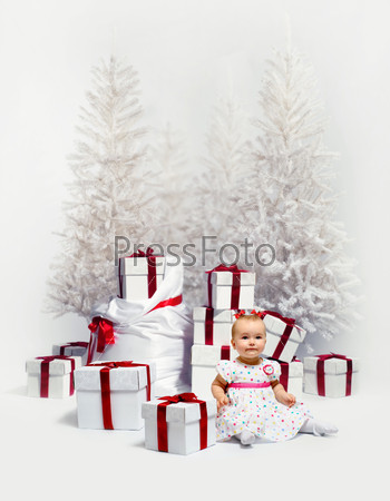 Adorable baby girl over christmas trees and heap of gift boxes background