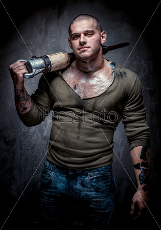 Muscular tattooed man with jackhammer posing over grey background