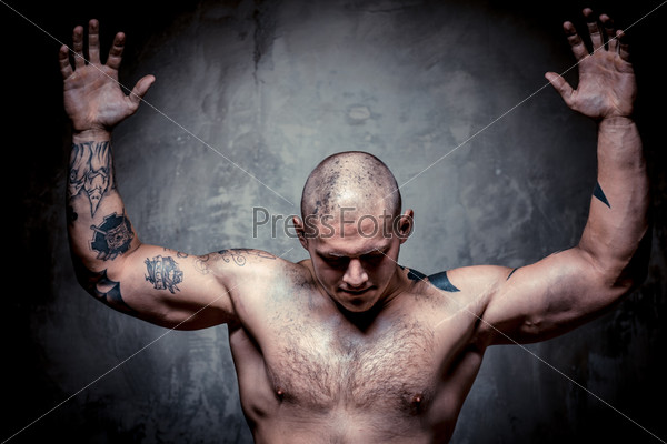 Muscular tattooed man with hands raised up