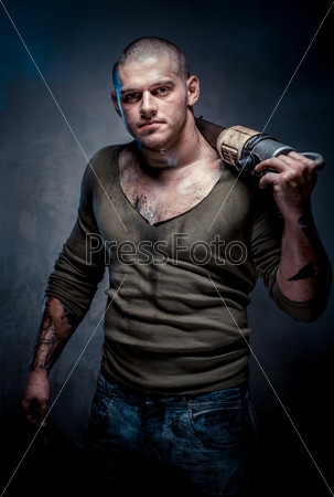Мускулистый мужчина с татуировкой, держащий отбойный молоток на плече на сером фоне