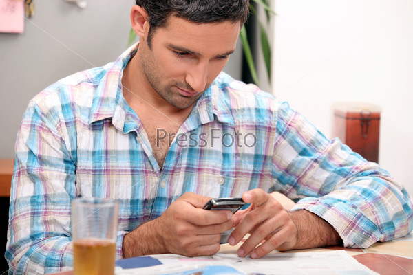 Man reading magazine and sending text message