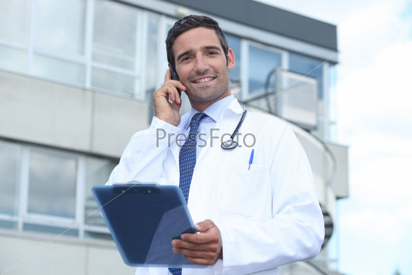 Мужчина-врач говорит по телефону у больницы