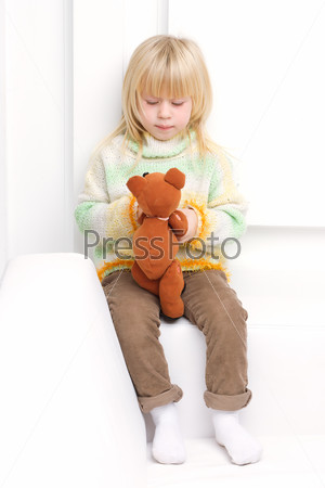 Little girl 3 years old sitting on a white couch, stock photo