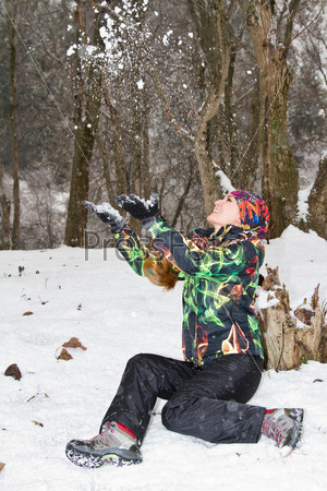 woman in a ski suit throwing snow in the winter outdoors