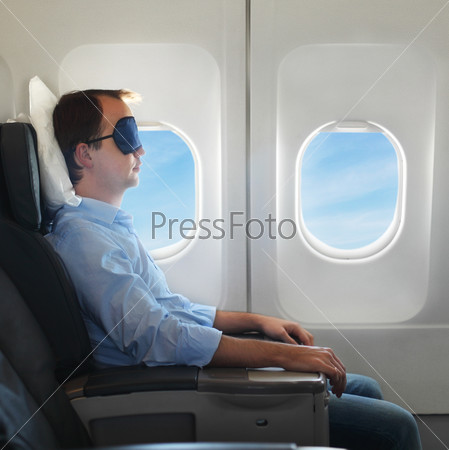 Portrait of man relaxing in sleaping mask in the airplane