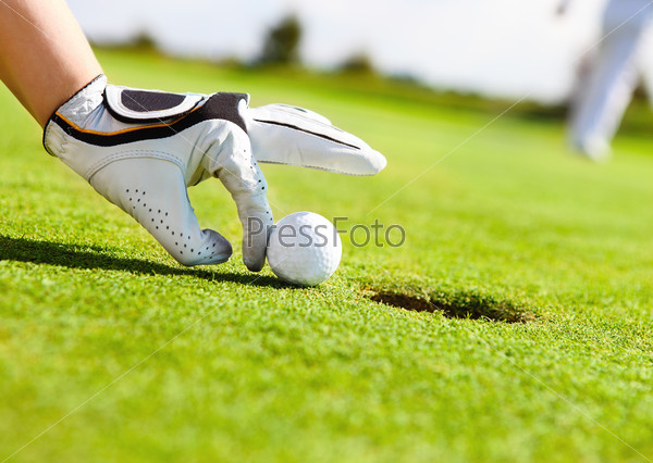Golf player woman pushing golf ball into the hole