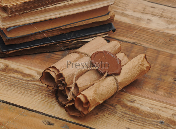 Pile of old books and scroll on wood background