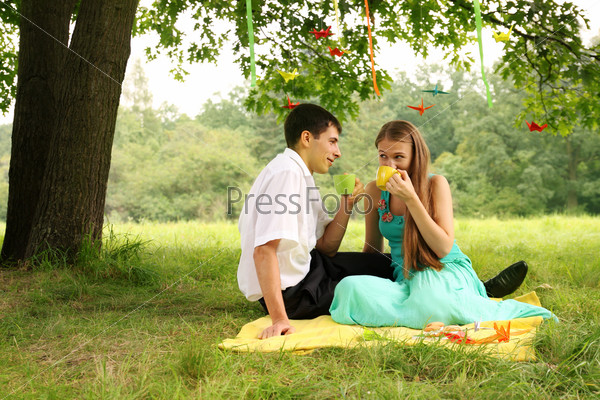 Couple drinking tea in the park under a tree