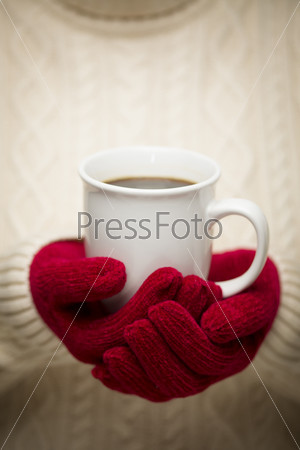 Женщина в свитере и красных перчатках, держащая чашку кофе