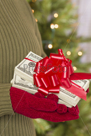Женщина в варежках держит деньги с красной лентой