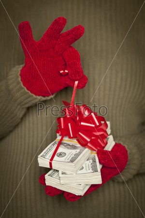 Женщина в варежках держит деньги с красной лентой