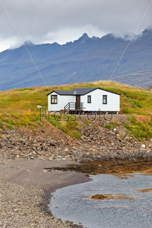 White Siding House at coastline ?in East Iceland. Vertical shot