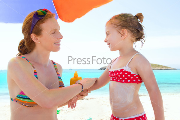 daughter and mother in beach with sunscreen in bikini