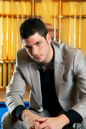 handsome man with suit sitting posing in billiard pool in club