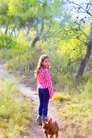 Children girl walking in the pine forest with dog
