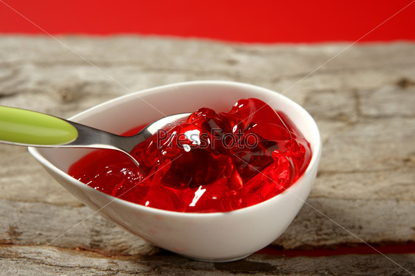Bowl full of strawberry red sweet jelly and green spoon