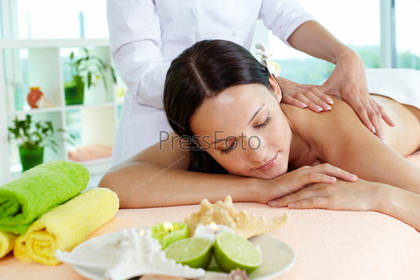 Photo of a girl lying on the massage table, massage therapist doing the procedure