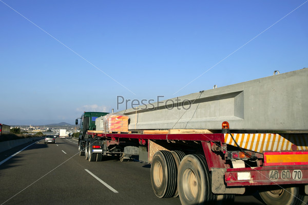 Heavy transportation truck lorry carrying a concrete big beam on a road in Europe