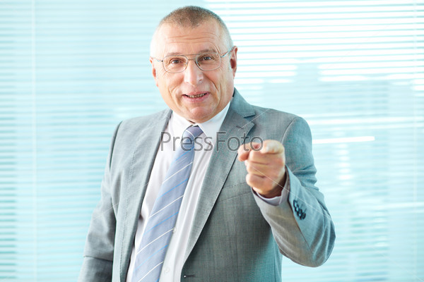 Portrait of elderly businessman pointing and looking at camera