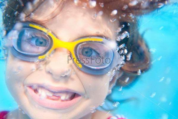 children girl swimming underwater with goggles and funny gesture