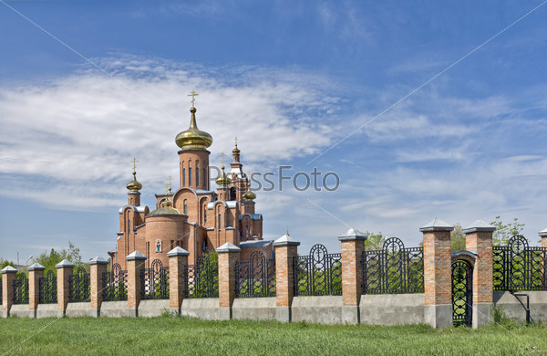 Cathedral with gilded domes against the blue sky behind the iron fence.