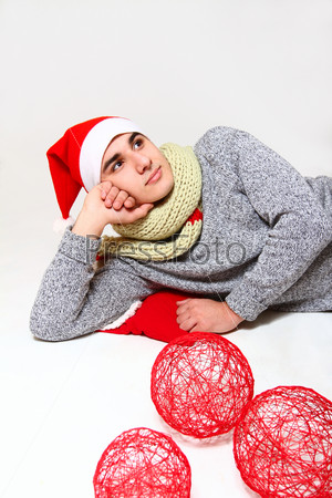 Young man with a scarf, hat santa claus and red balls o