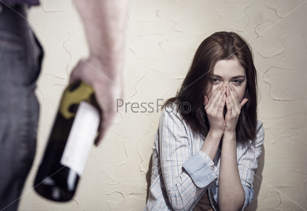 Woman victim of domestic violence and abuse. Woman scared of a man holding a bottle