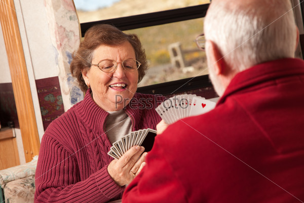 Happy Senior Adult Couple Playing Cards in Their Trailer RV